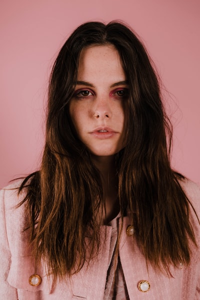 A woman dressed in a pink coat buttons
